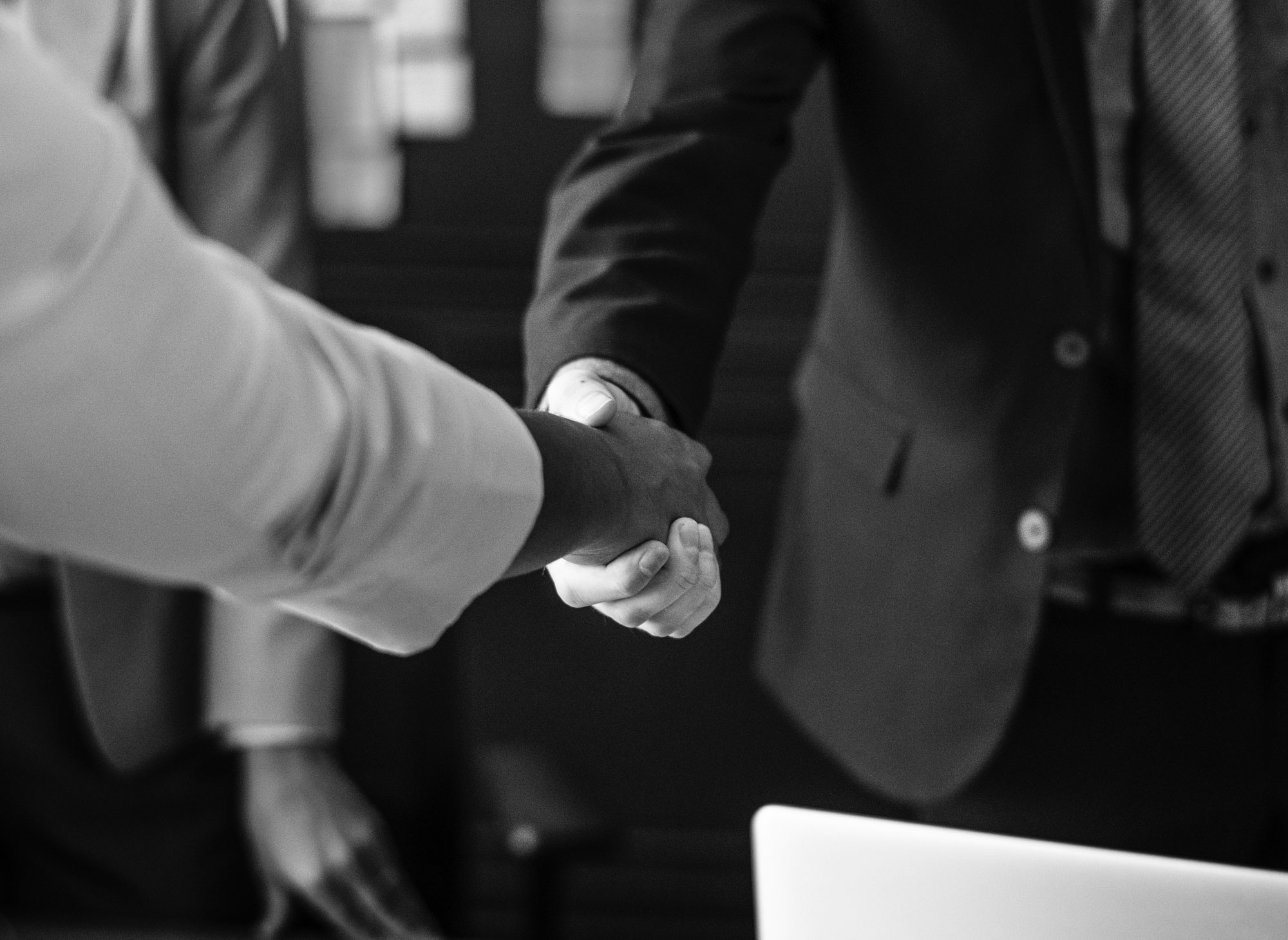 Two people shaking hands over a table.